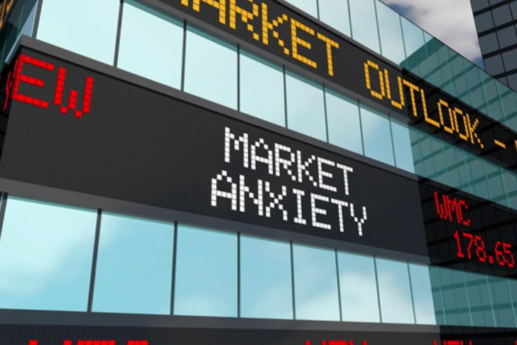 A digital stock ticker display on a building showing 'Market Anxiety' and 'Market Outlook' in a city setting
